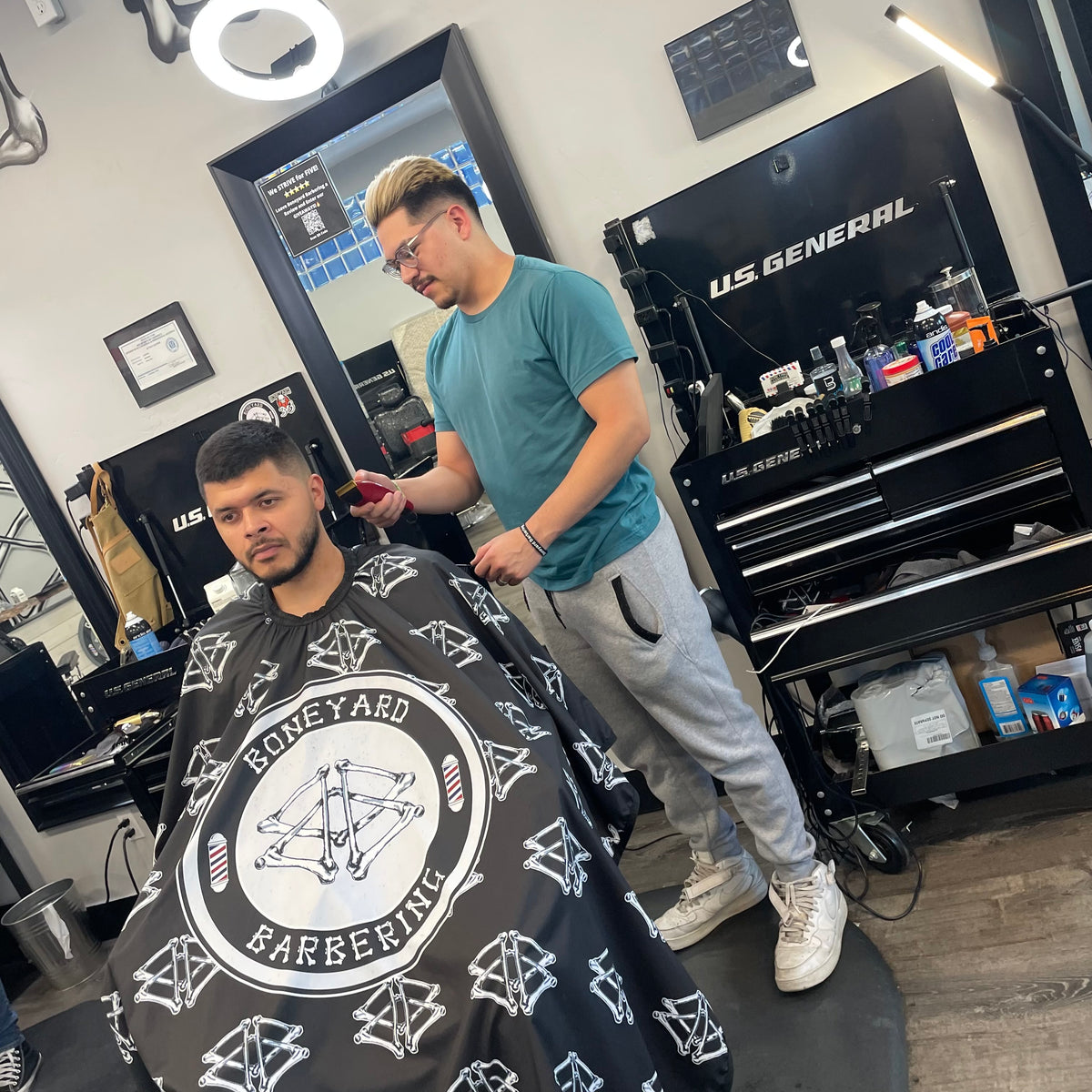 Boneyard barber finishing a haircut in the shop