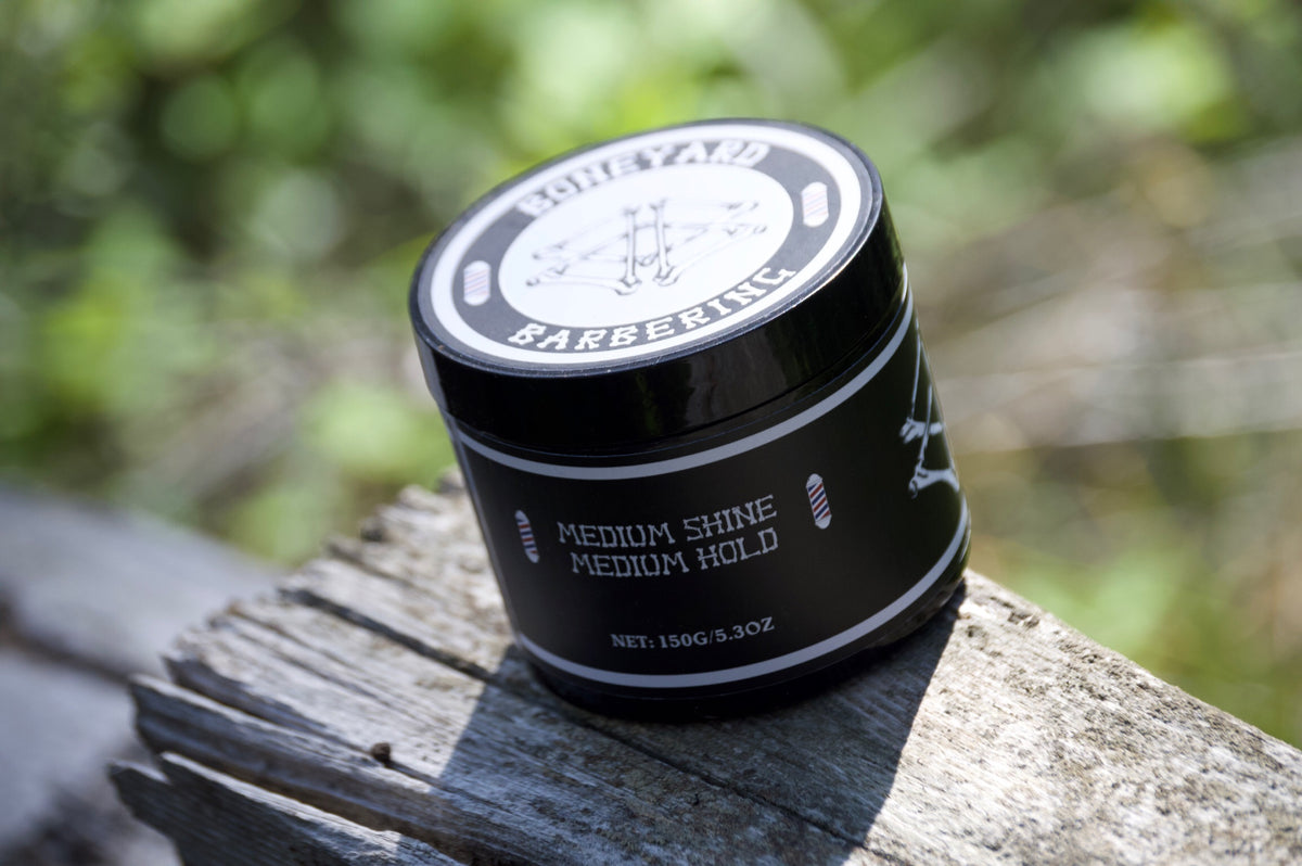 Boneyard Shine Pomade jar on a wooden post outdoors
