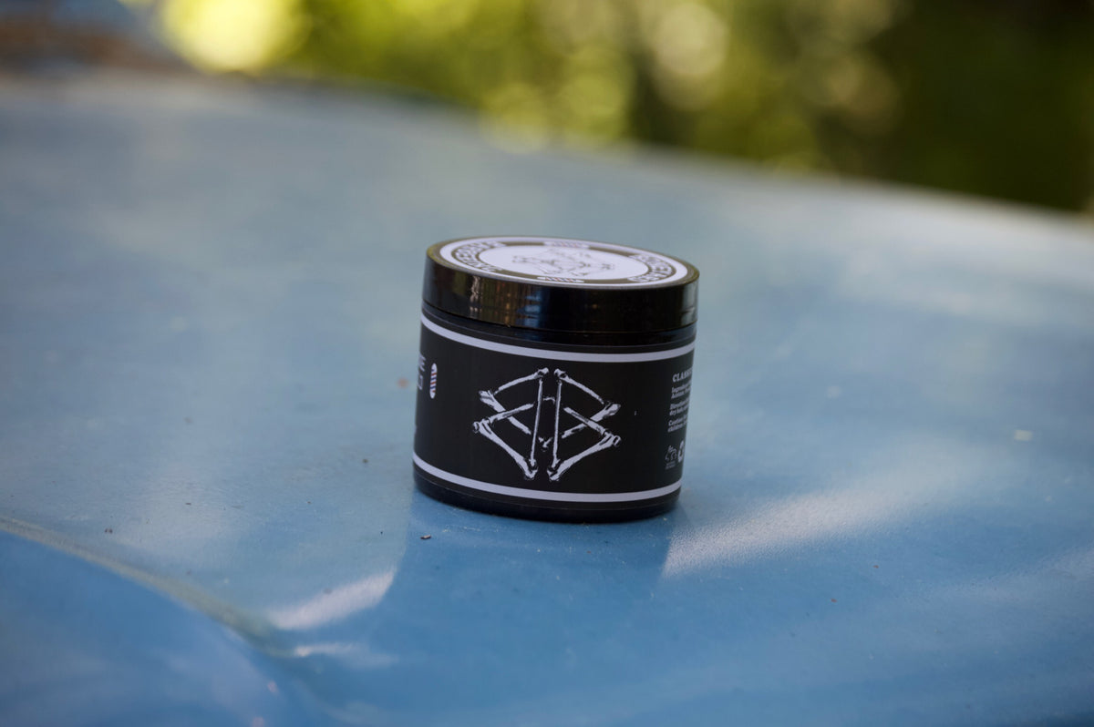 Boneyard Shine Pomade jar outdoors on a wooden surface